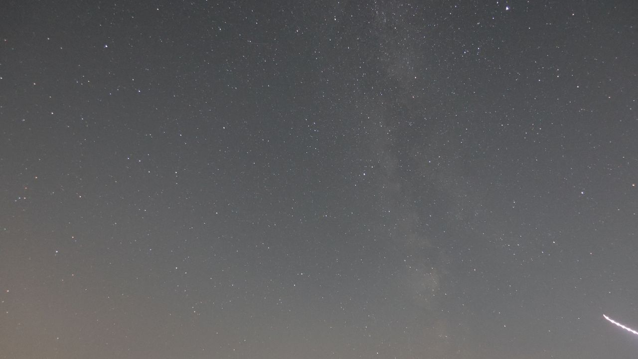 An astrophoto showing the core of the Milky Way and a light streak from an airplane, taken with the Canon Powershot V1.