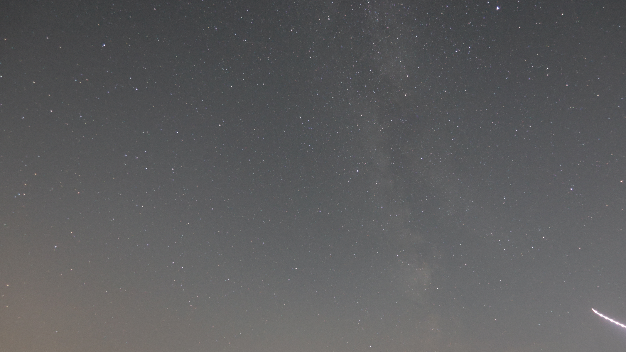An astrophoto showing the core of the Milky Way and a light streak from an airplane, taken with the Canon Powershot V1.