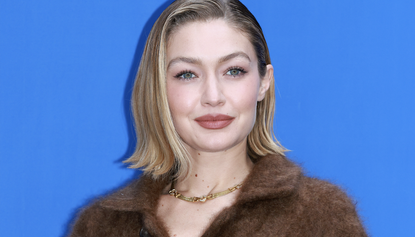 Gigi Hadid poses for media during the &quot;Guest In Residence&quot; Seoul pop-up store opening at Tom Greyhound on November 04, 2024 in Seoul, South Korea wearing a brown wrap coat and loafers