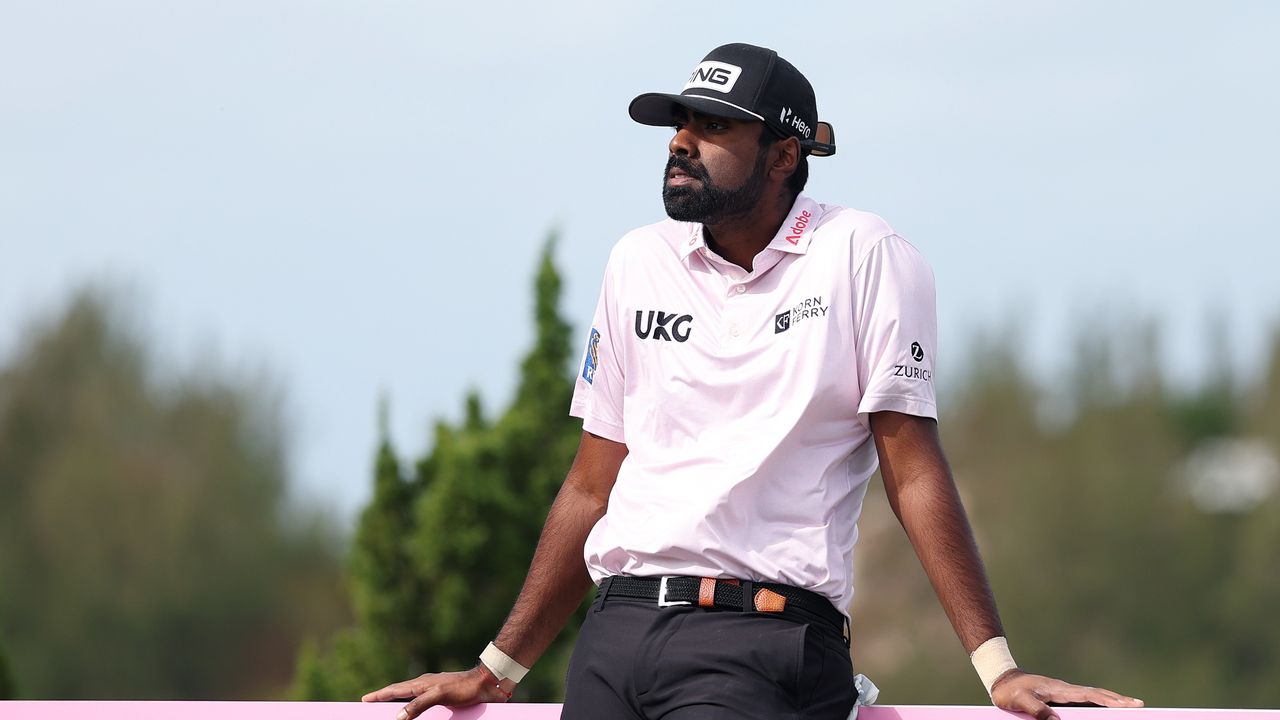 Sahith Theegala leans up against an advertising board by a tee box at the Butterfield Bermuda Championship in 2025