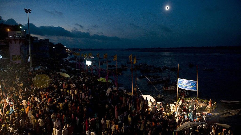 Thousands of people are gathered to watch a solar eclipse in the dark sky above