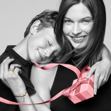 Mother and child embracing holding a Pandora gift box and wearing gold Pandora rings and a bracelet