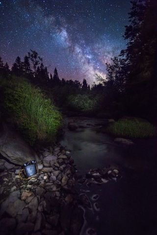 The magnificent night sky photo captures the Milky Way rising over the Connecticut River in Pittsburg, New Hampshire. It was taken by photographer Charles Cormier on a recent camping trip. The binoculars resting on the rocks in the foreground belonged to