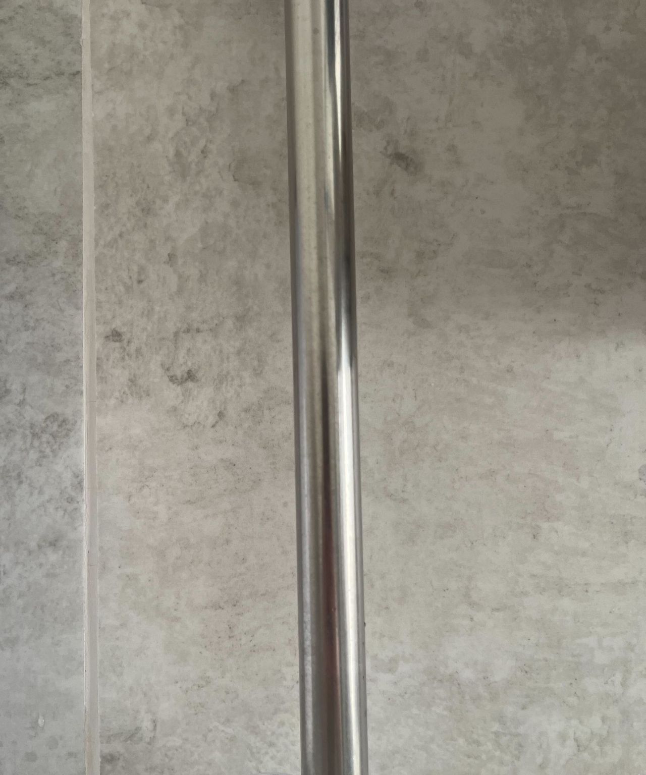 The metal bar that holds a shower head covered in water marks