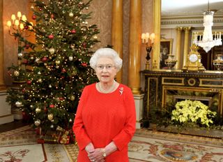 Queen Elizabeth II stands in front of a Christmas tree at Buckingham Palace after recording her Christmas Day television broadcast