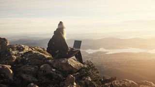 mountain weather forecast: hiker with laptop on mountain