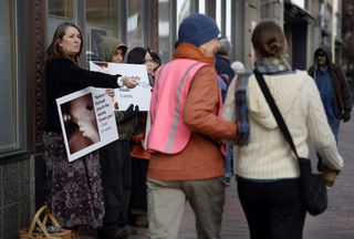 A clinic escort directs a woman seeking care. Protestors line the walk.