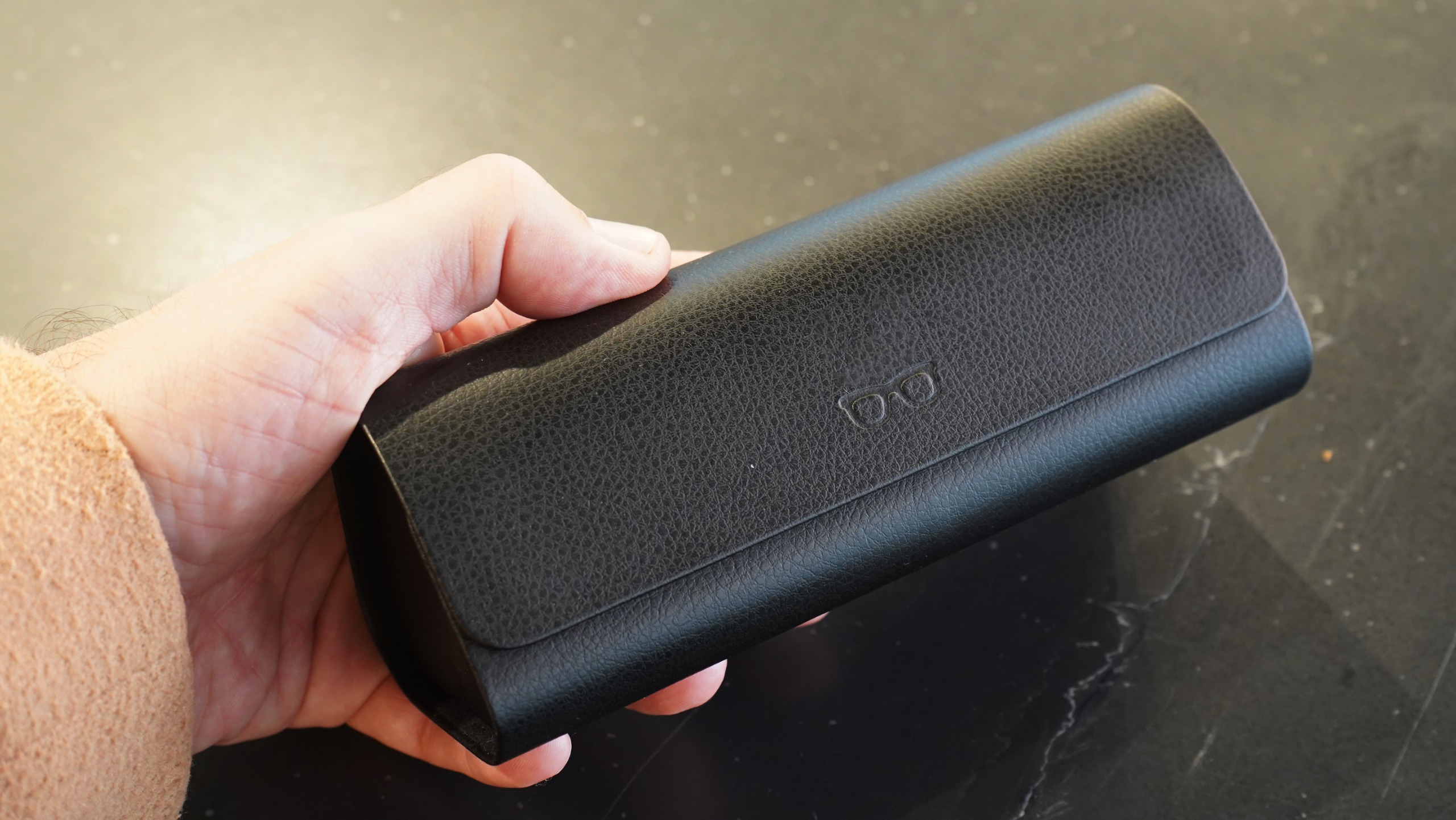 Charging case for Meta Ray-Ban Display glasses held in Adam Juniper's hand