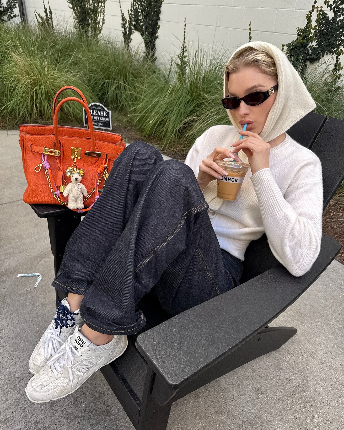 Elsa Hosk wearing a cream sweater, dark denim jeans, Miu Miu sneakers, and a knit head scarf