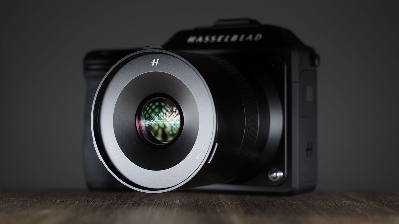 Hasselblad XCD 75P lens on a Hasselblad X2D camera, on a wooden surface against a dark background