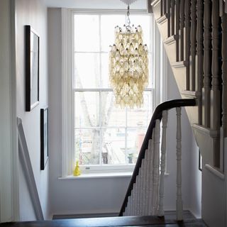 staircase with white walls and chandelier