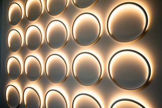 Five columns / four rows of illuminated circular plate-sized rings on a wall.