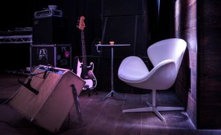 A white chair next to a speaker and a guitar