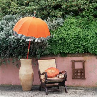 orange parasol in terracotta pot with cane weave chair