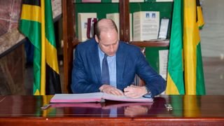 Prince William signs the visitor book during a meeting with the Prime Minister of Jamaica