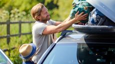 Man and child getting ready for a road trip and putting luggage into a car