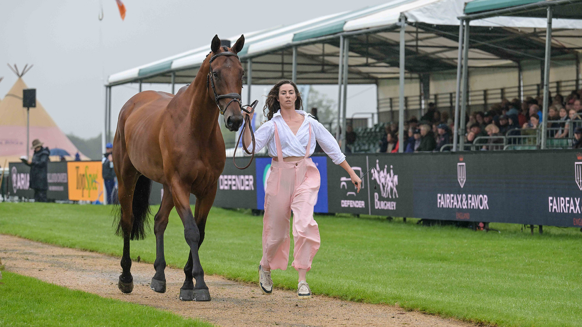 Tayla Mason, a rider wearing pink baggy trousers and a white top, trots up bay horse Centennial at Burghley Horse Trials first trot-up 2026