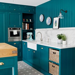 kitchen platform with white marble blue cabinet with book shelves potted plants and painting