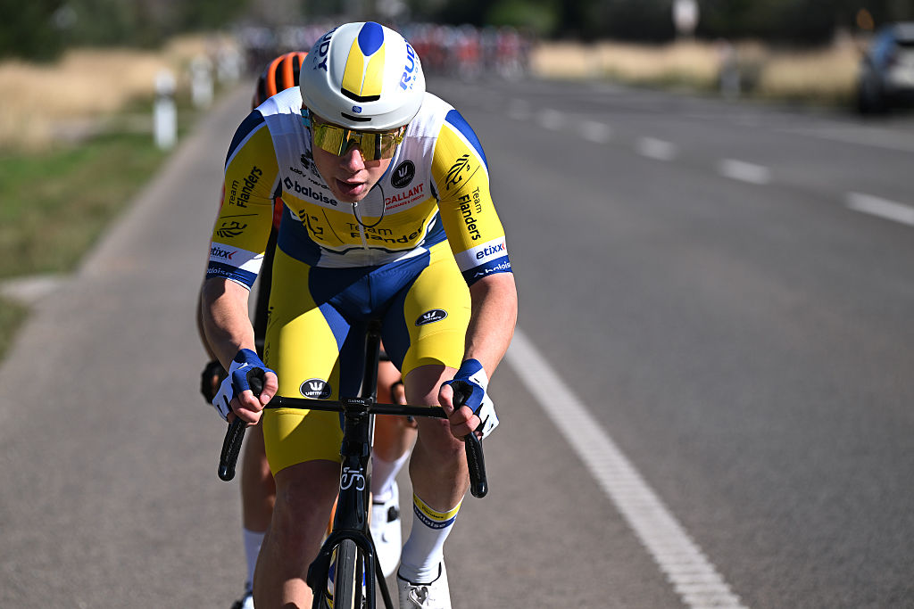 Man cycles on a road in a yellow and blue jersey