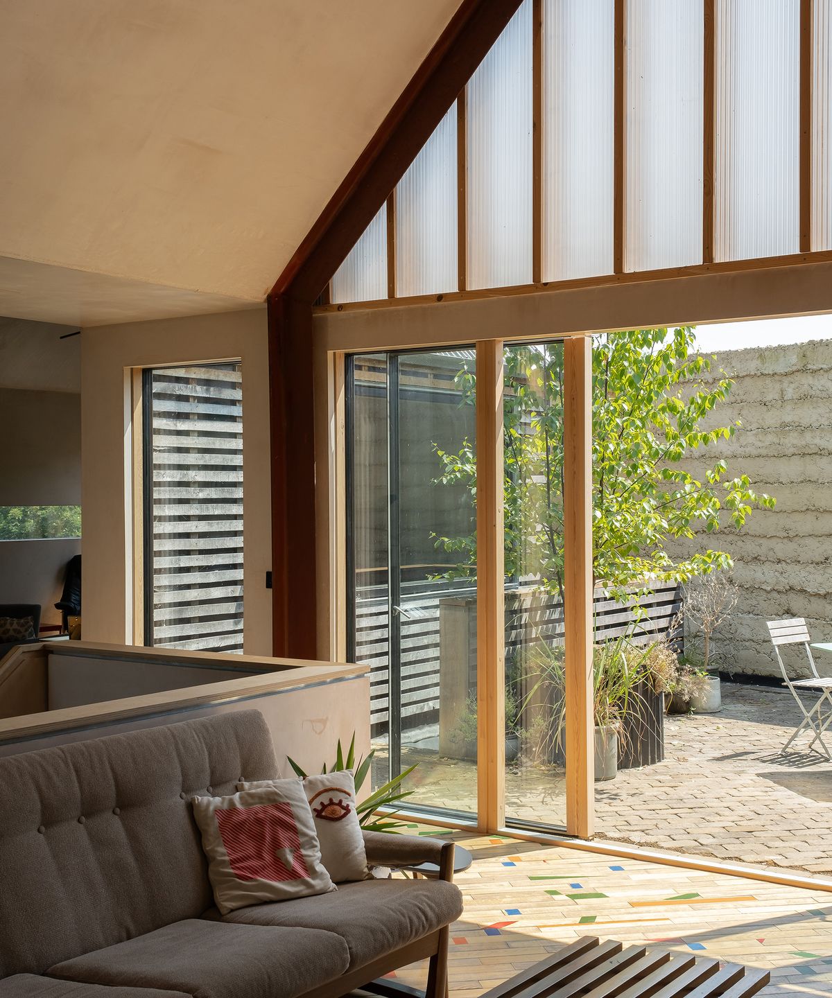 Timber framed glass sliding doors leading to a sunny courtyard from a living room in a self build home