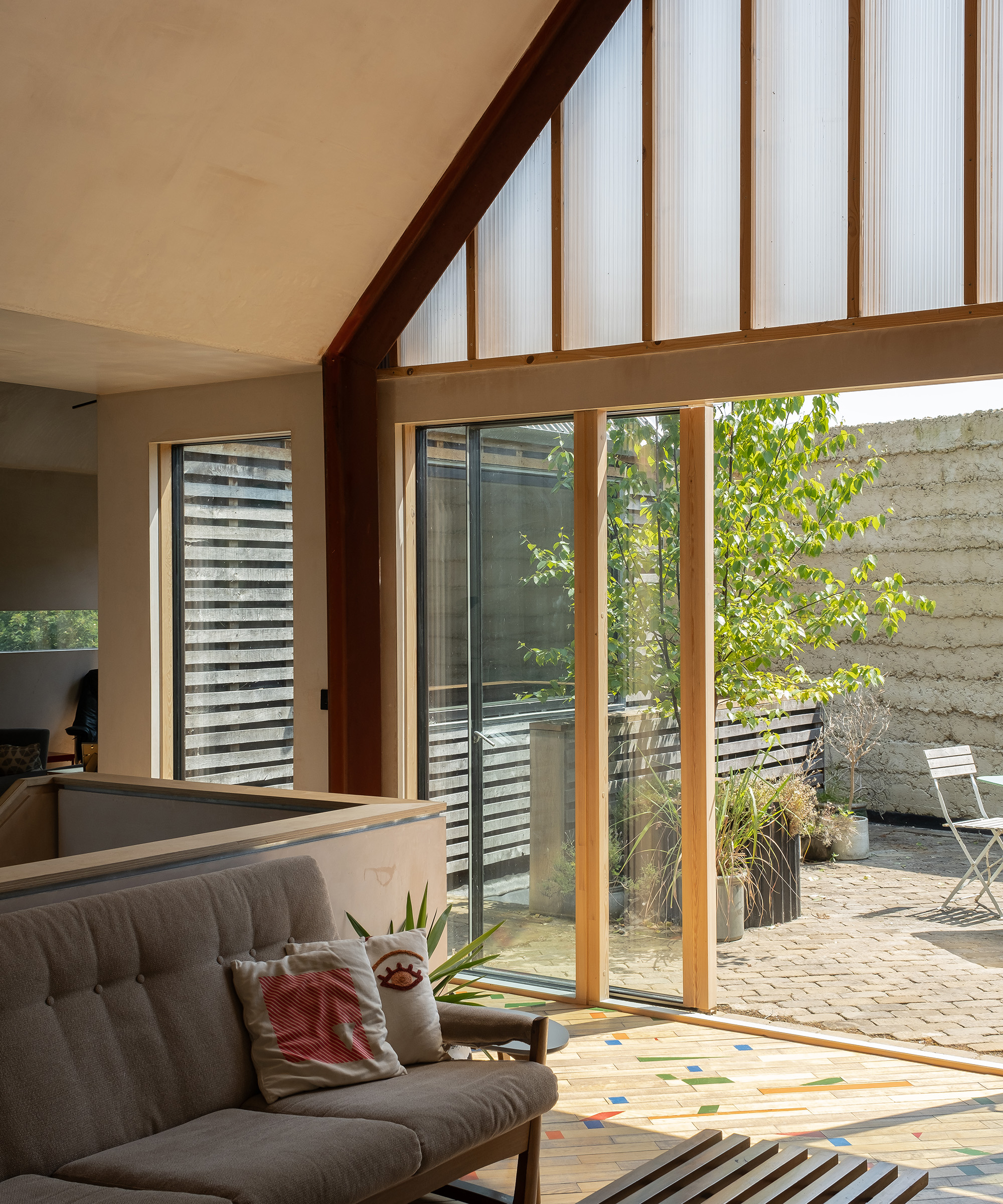 Timber framed glass sliding doors leading to a sunny courtyard from a living room in a self build home