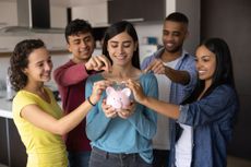 A group of happy friends each putting money into a piggy bank