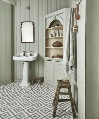 White wall paneled bathroom with white basin, wooden stools and bathroom cabinet by Carpetright