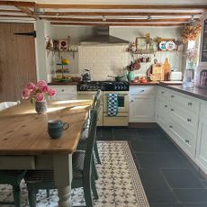 Country kitchen with wooden beams, range oven, wooden countertops and tiled splashback