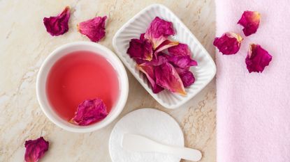 A tray displaying rosewater and rose petals to illustrate a guide to rosewater for face