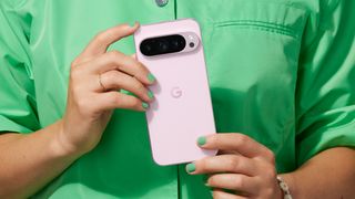 Une personne habillée en vert tenant le Google Pixel 9 Pro rose.