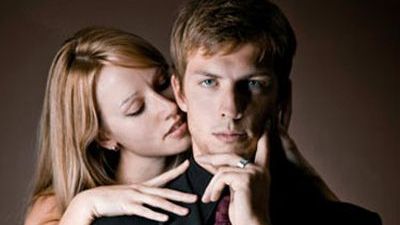 man in suit with woman behind him nuzzling his neck