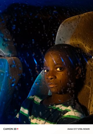 A child looks out of a car window in the rain