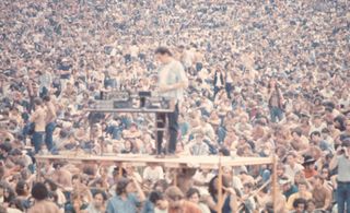 A sound man stands on scaffolding with his equipment in front of the crowd at the Woodstock music festival in August 1969