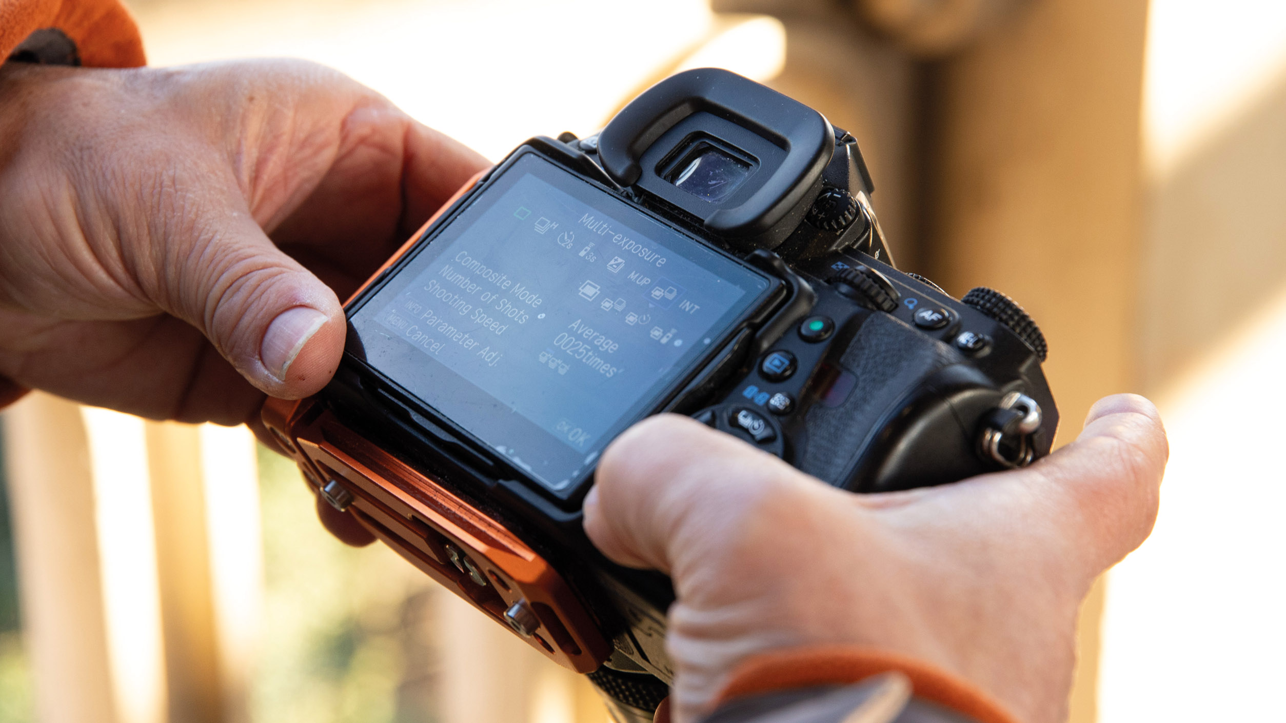 A man holding a camera outdoors showing the multi exposure menu on-screen