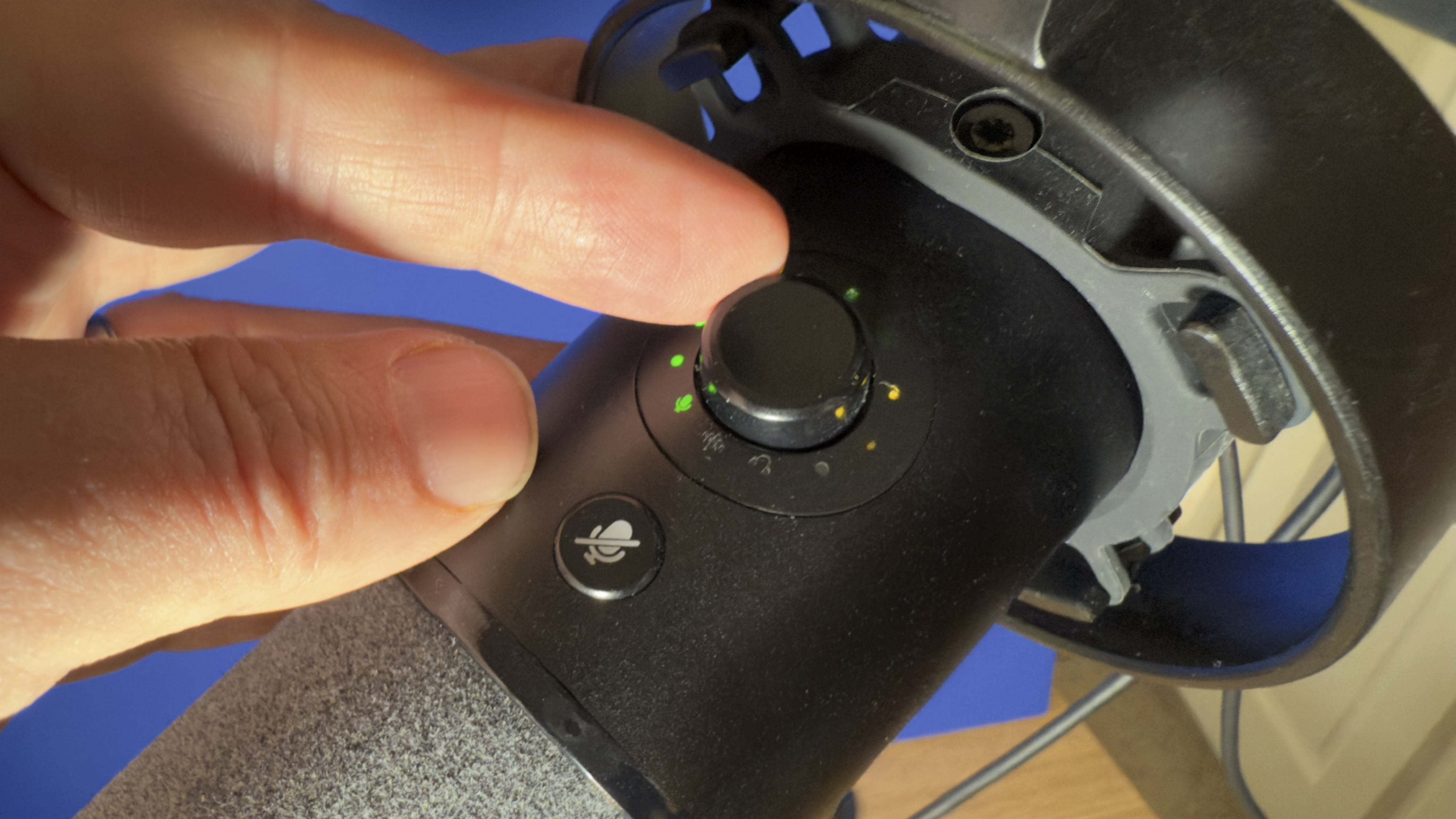 A finger rotates the control knob on the mic to adjust sound input levels. Green lights indicate the strength of the sound level setting