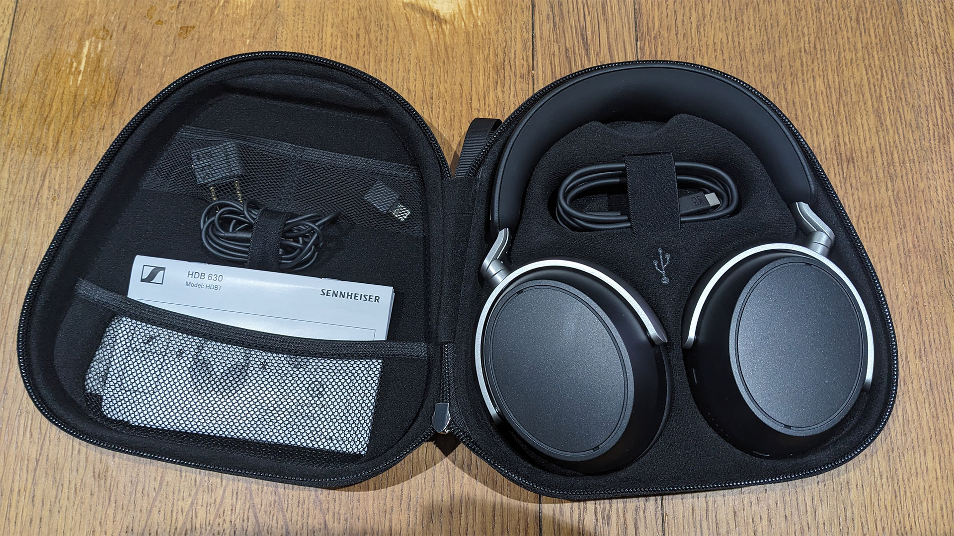 Sennheiser HDB 630 over-ear headphones in open case on wooden surface