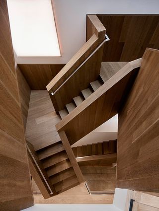 A wooden staircase zigzags up through the interior unifying the floors