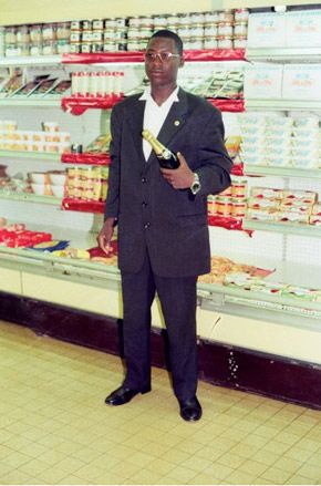 African man wearing suit holding a bottle