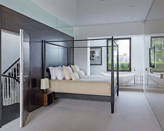 bedroom with black bed frame and free standing tub
