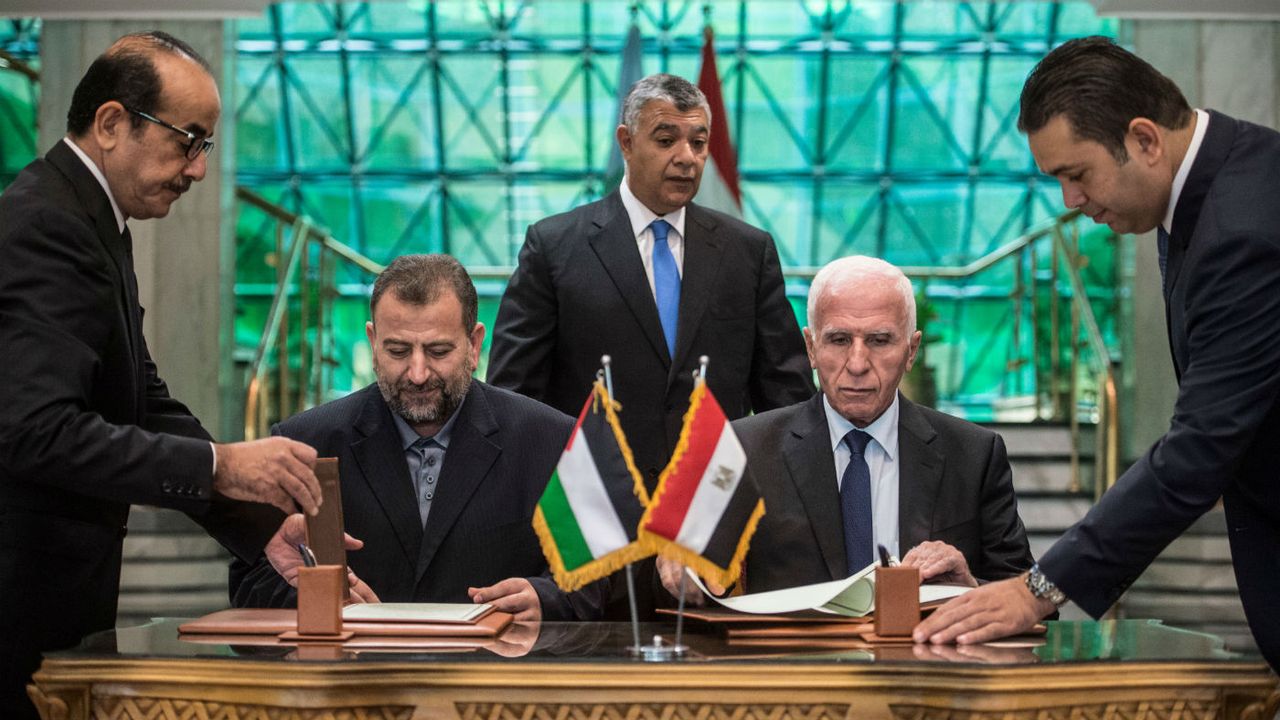 Fatah&amp;#039;s Azzam al-Ahmad (right) and Saleh al-Aruri (left) of Hamas sign the reconciliation deal