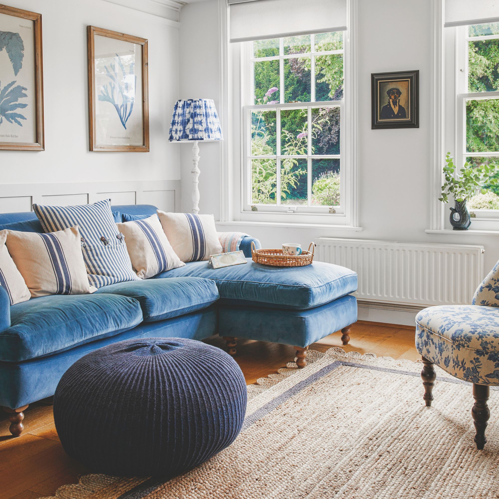 White painted living room with a bright blue sofa and round pouffe on the floor in front of it, on a jute rug