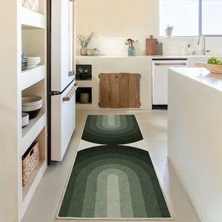 A cream rug with sage green arches is sitting in a cream kitchen