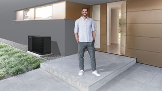 Man stood by front door of contemporary home with black heat pump in background