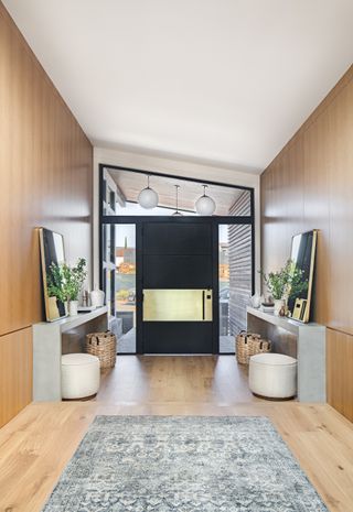 entryway with wood panelled walls and floor, rug, consoles, sloped ceiling