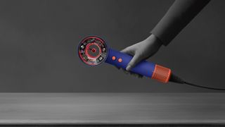 A hand holding the Dyson Supersonic Nural hair dryer