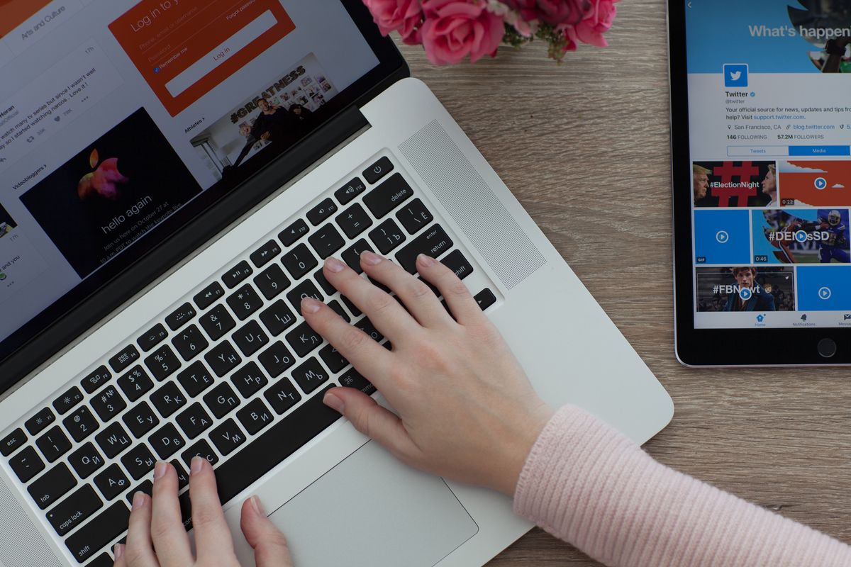 A person using an Apple Macbook alongside an iPad