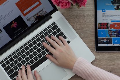 A person using an Apple Macbook alongside an iPad