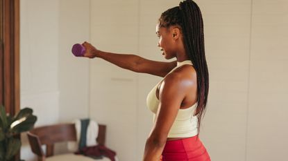 Home workouts that build muscle: A woman lifting a weight