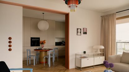 An open-plan living and kitchen space toys with colour and calm &ndash; white walls with bright furniture.