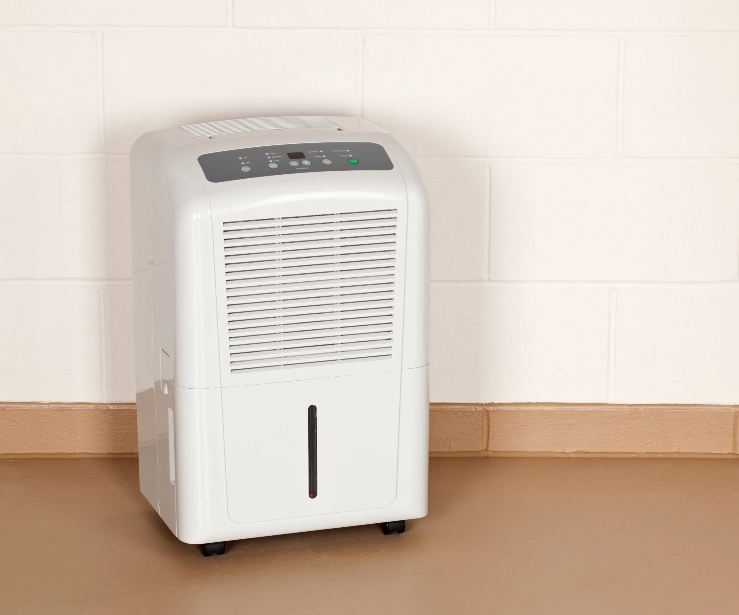 Dehumidifier in front of a wall on a brown vinyl floor and a pale wall